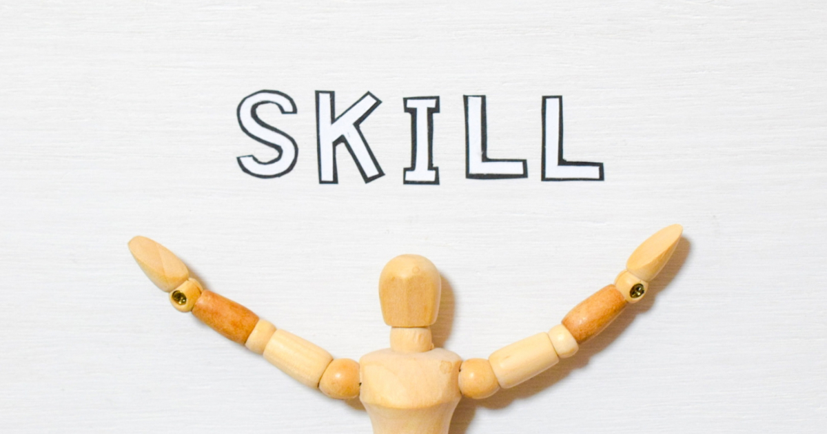 両手を上げた木製の人形と、その上に描かれたSKILLの文字